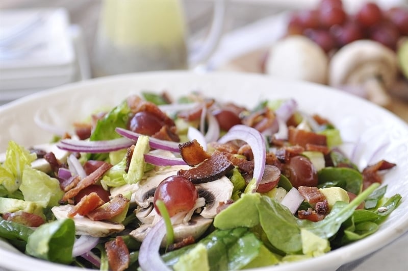 Salad with lettuce, spinach, red onion, mushrooms, bacon, and grapes