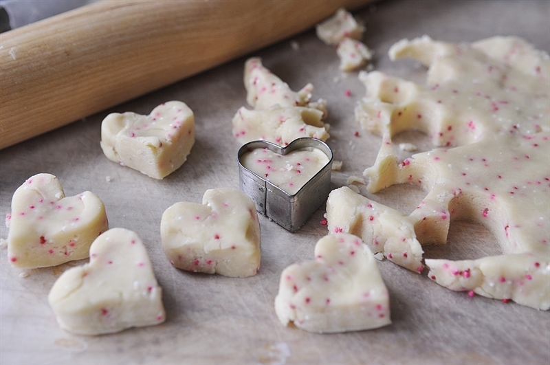 cutting shortbread dough into heart shaped cookies