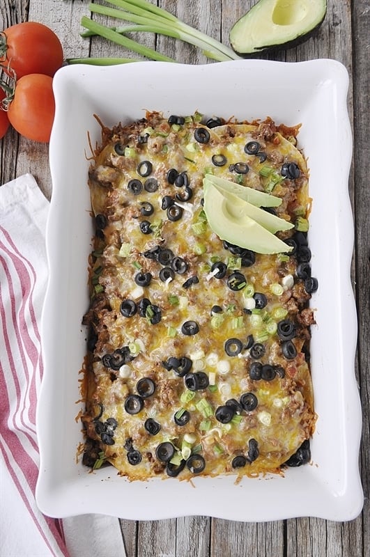 Mexican casserole in white serving dish garnished with avocado slices