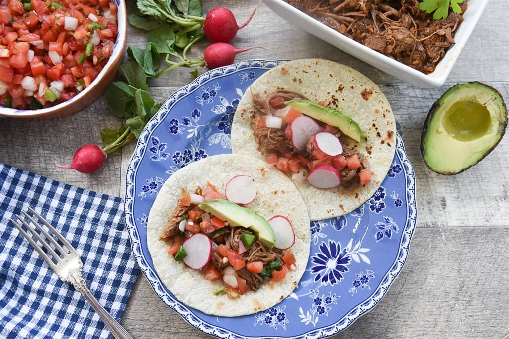 two brisket tacos on a blue and white plate