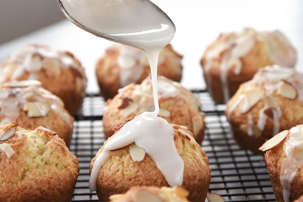 drizzling lemon glaze on muffins