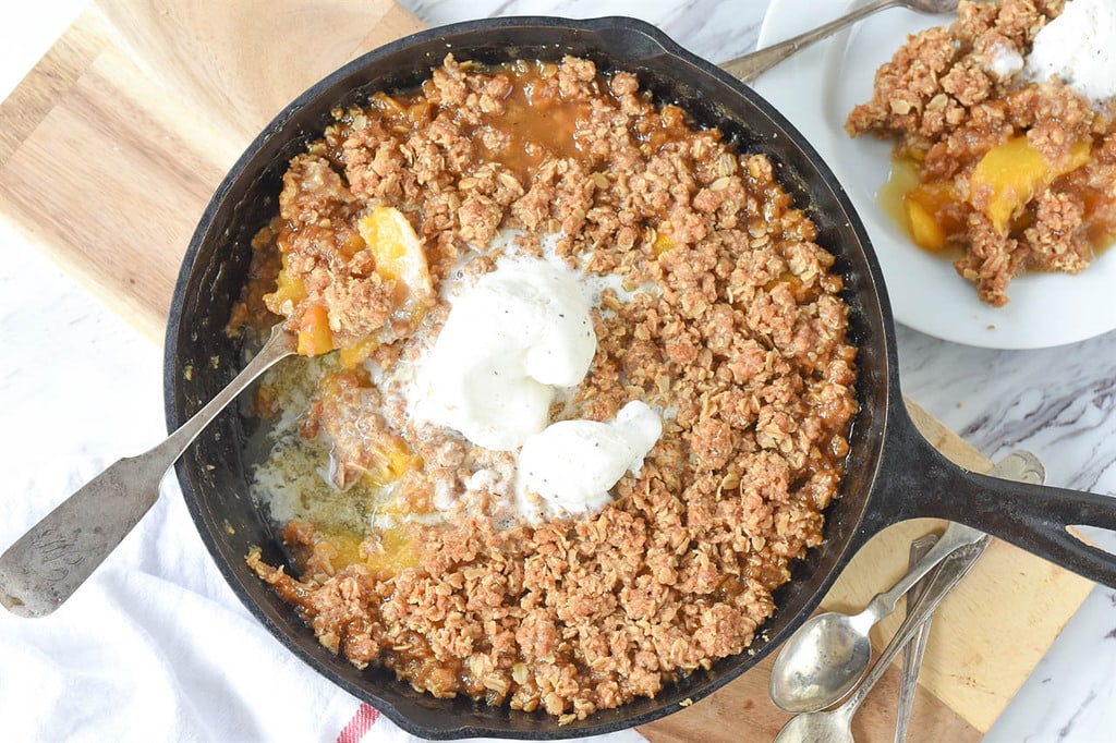 eating Peach Crisp with ice cream out of a cast iron skillet