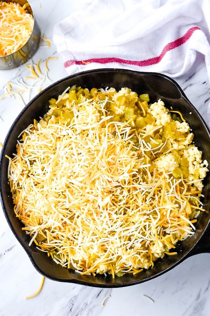 Green Chili Egg Casserole topped with cheese in a cast iron skillet