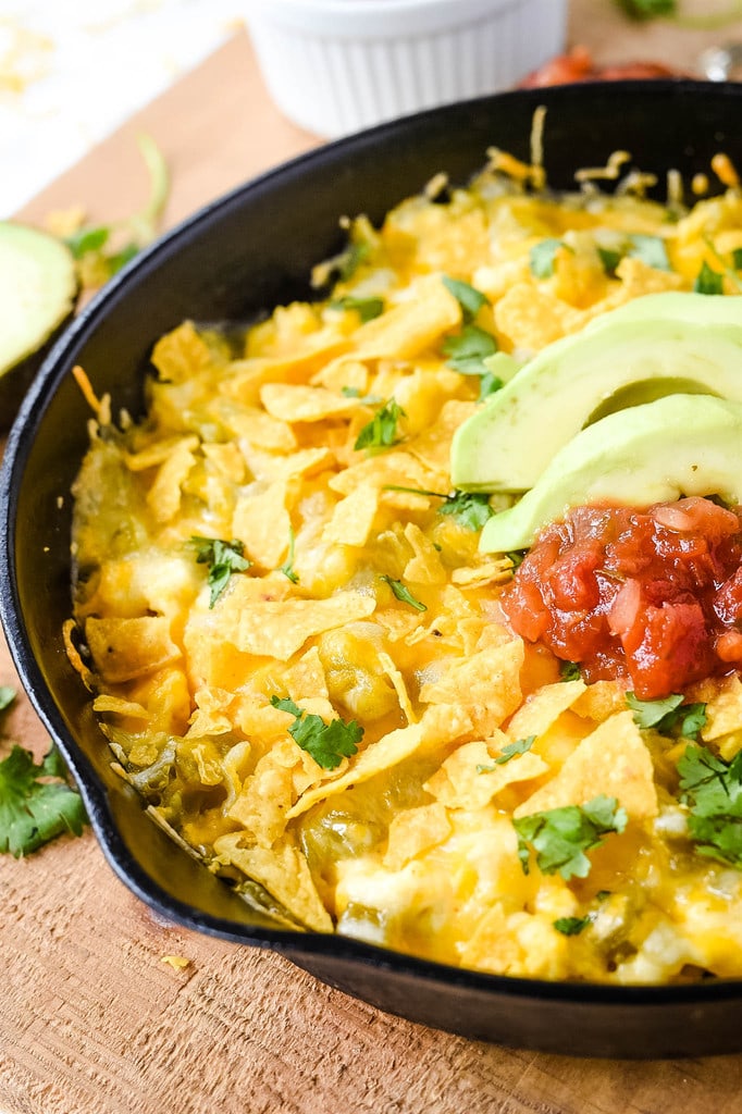 egg casserole topped with chips salsa and avocado in a cast iron skillet