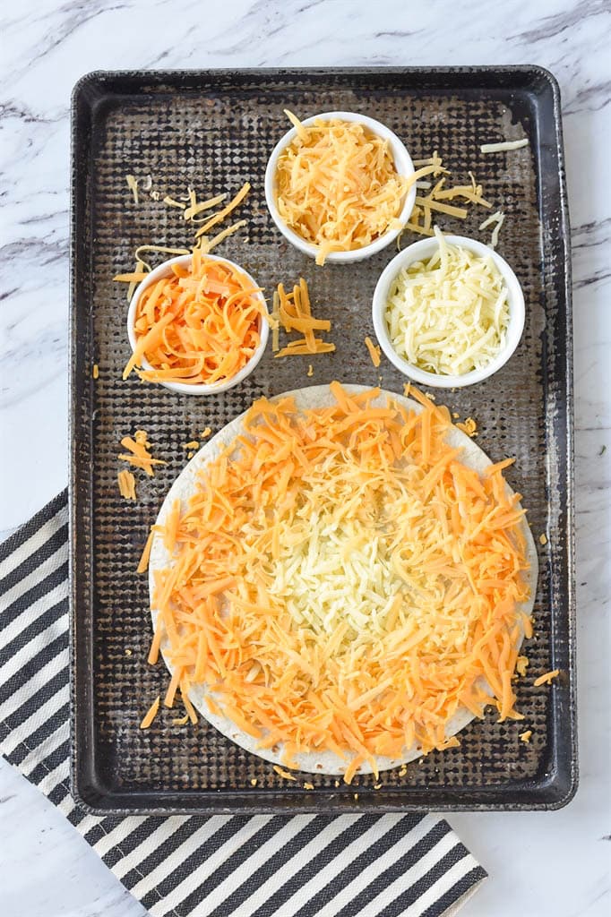 Candy Corn Quesadilla on a baking sheet with shredded cheese