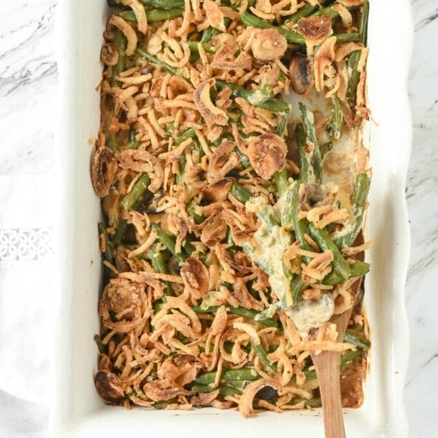 Green Bean Casserole in a white dish with a wooden spoon in it