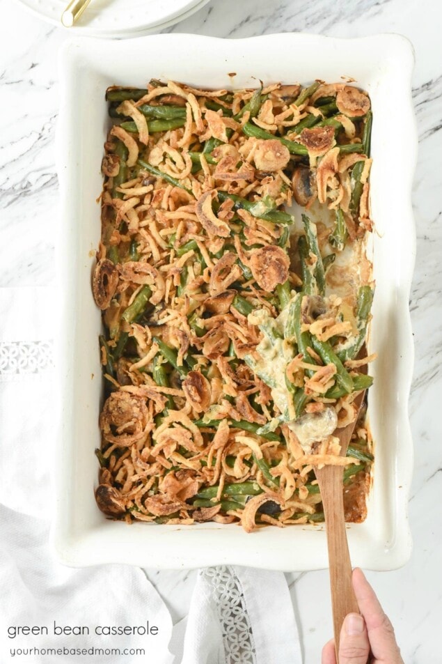 Green Bean Casserole in a white dish with a wooden spoon in it
