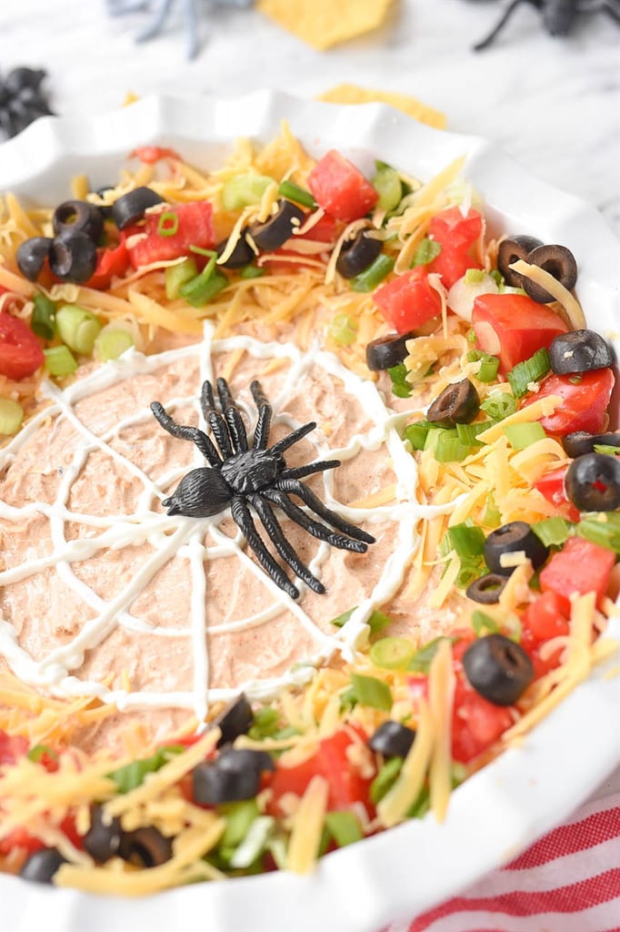 black plastic spider on a sour cream spider web 7 layer dip