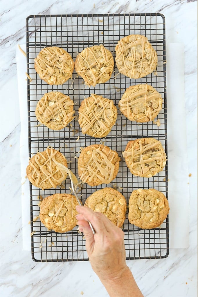 drizzling maple glaze over maple white chocolate chip cookies