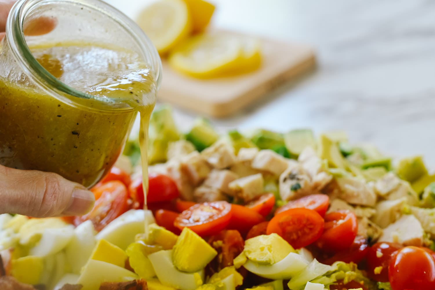 Pouring dressing on cobb salad