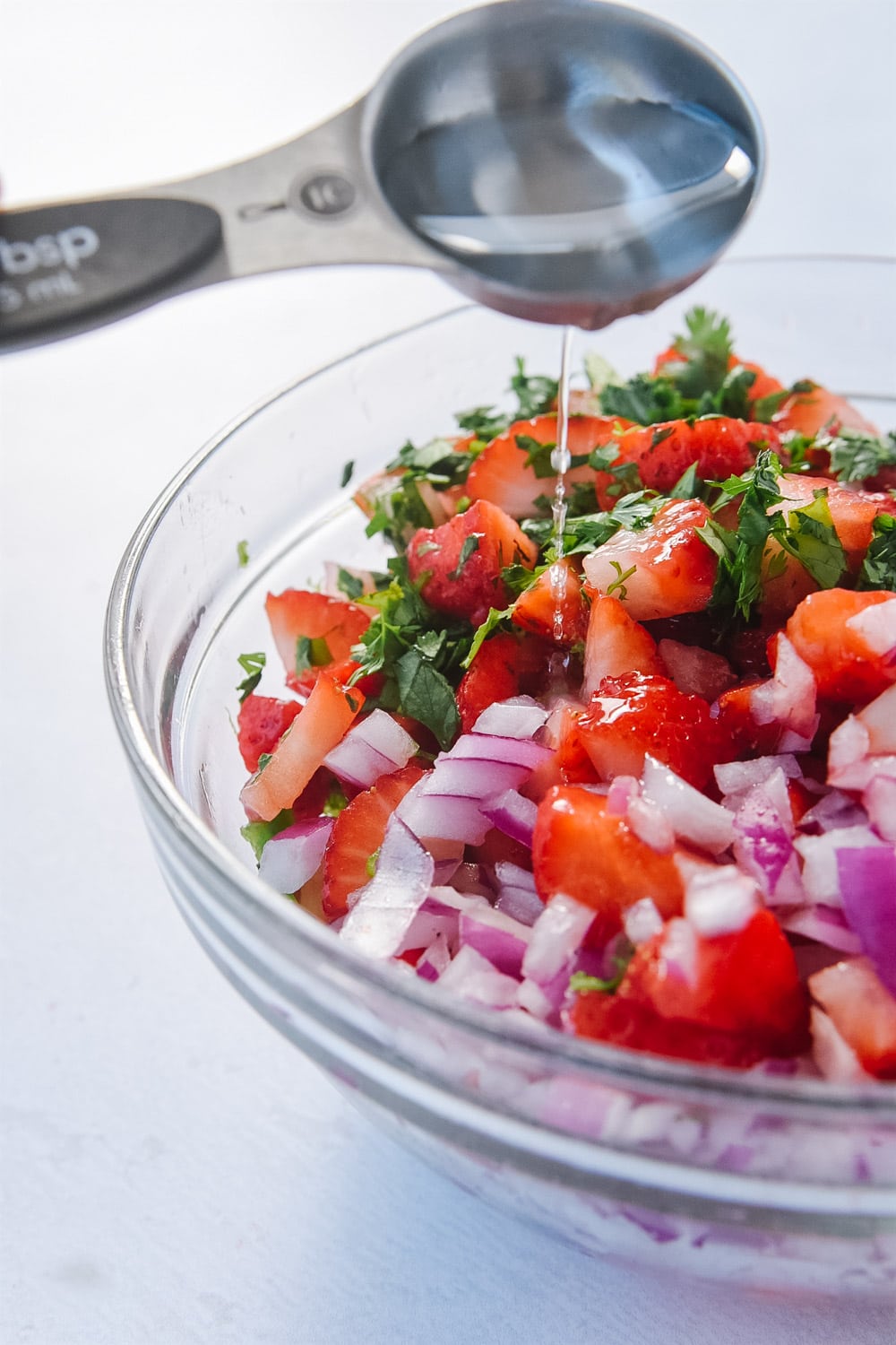 Pouring balsamic vinegar on strawberry salsa