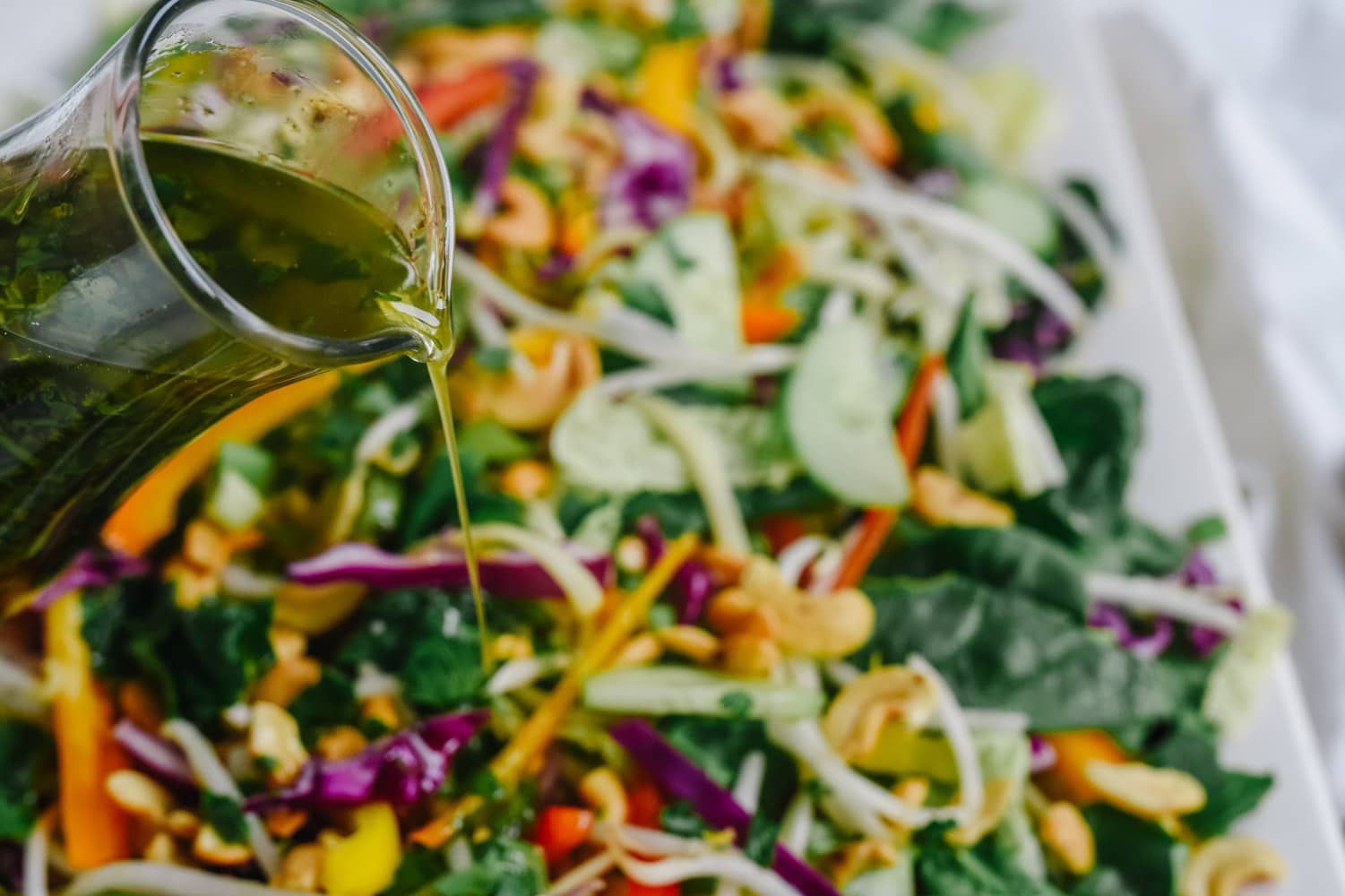 pouring dressing on asian noodle salad