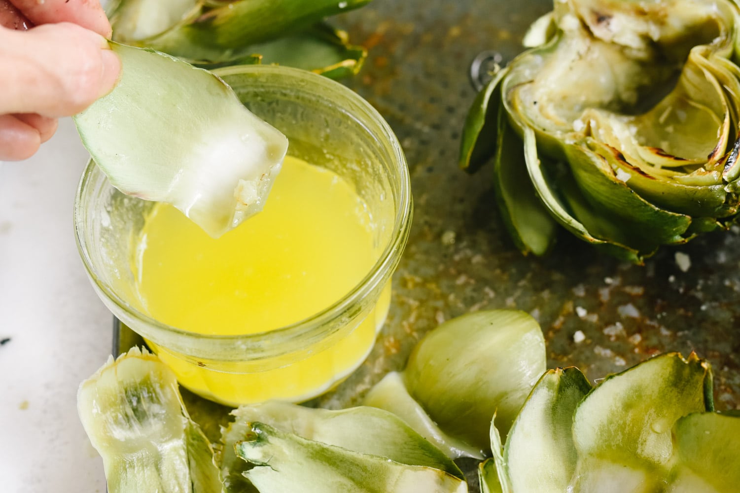 Dipping grilled artichokes in melted butter