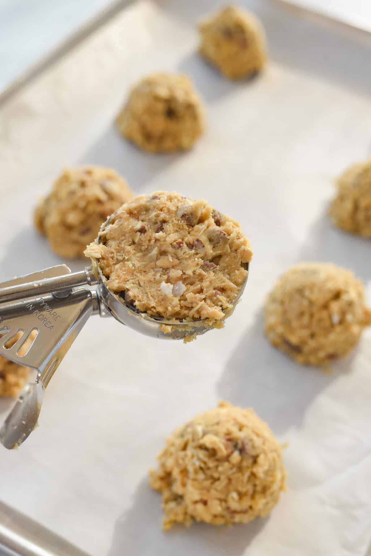 scooping cowboy cookie dough onto baking sheet