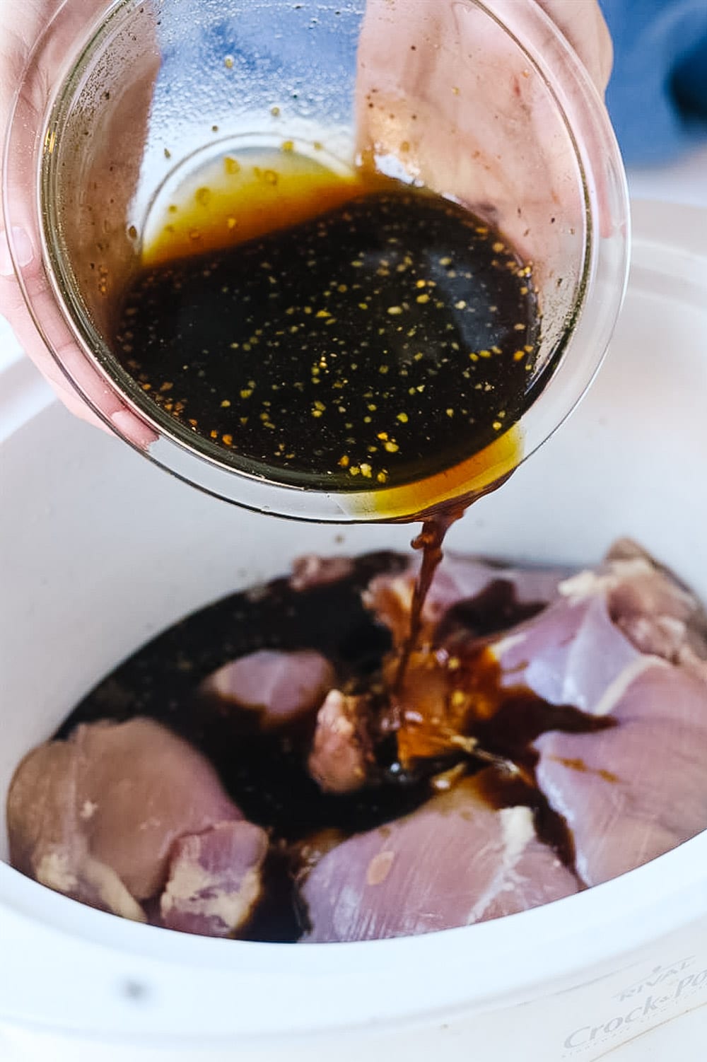 pouring teriyaki sauce over chicken crock pot