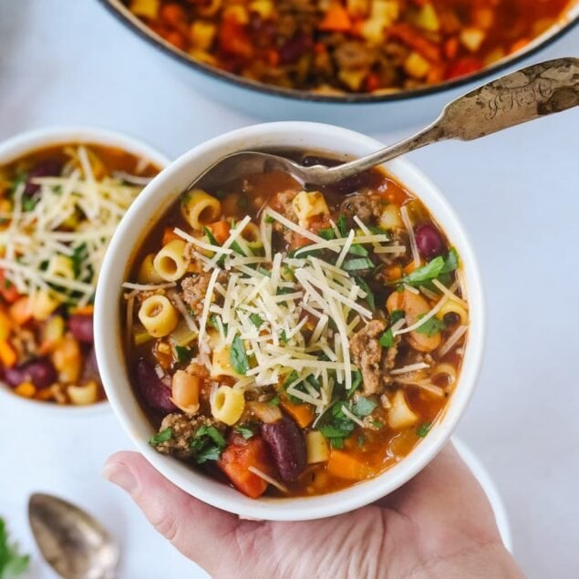 hand holding bowl of pasta e fagioli