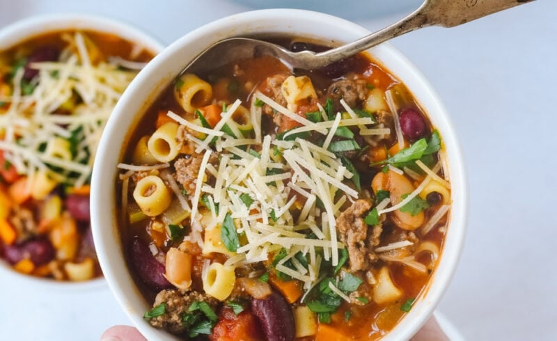 hand holding bowl of pasta e fagioli