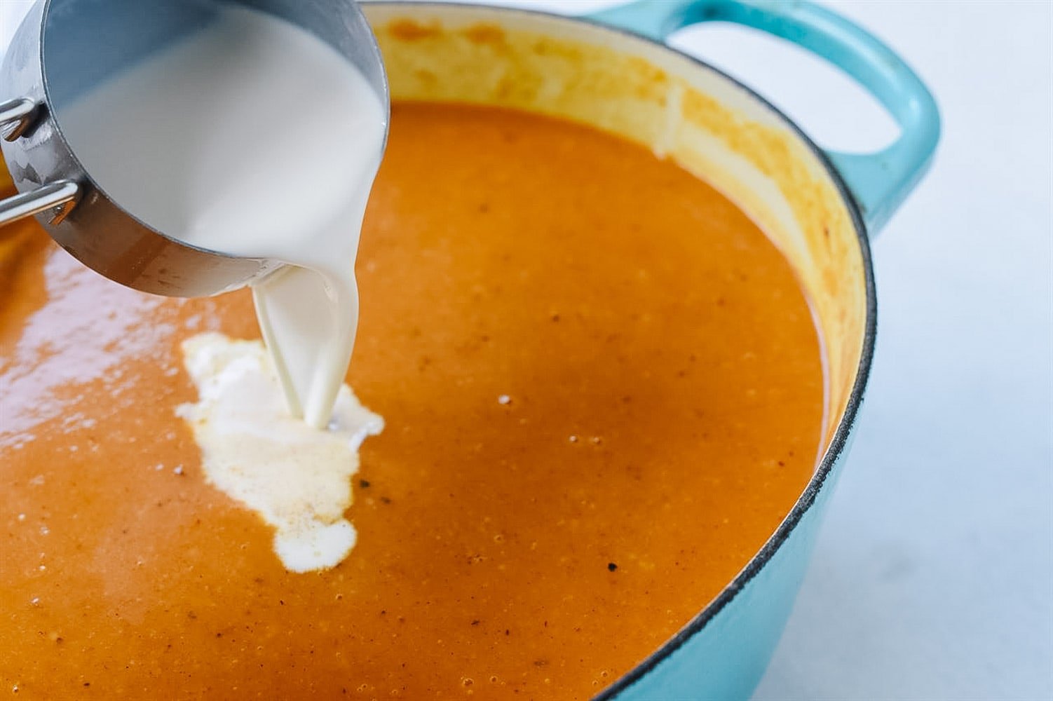 pouring cream into vegetable soup