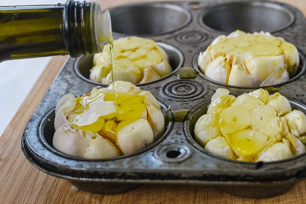 Drizzling oil over heads of garlic