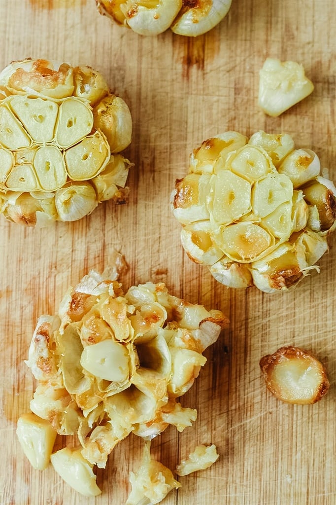 Heads of roasted garlic on a cutting board