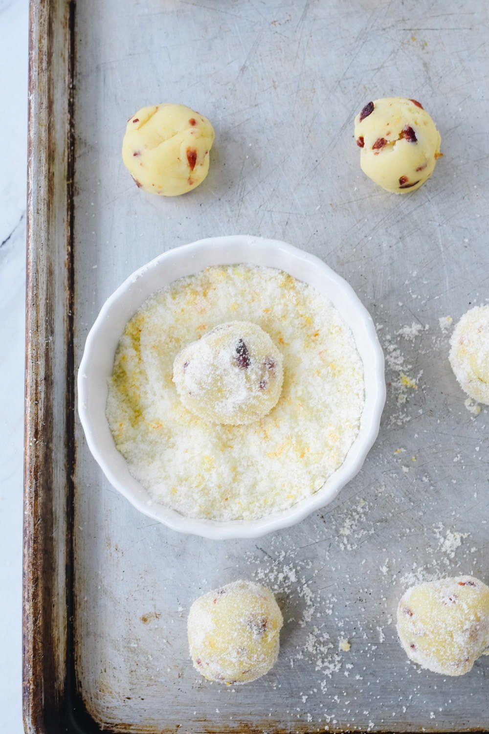 rolling orange cranberry cookies in orange sugar