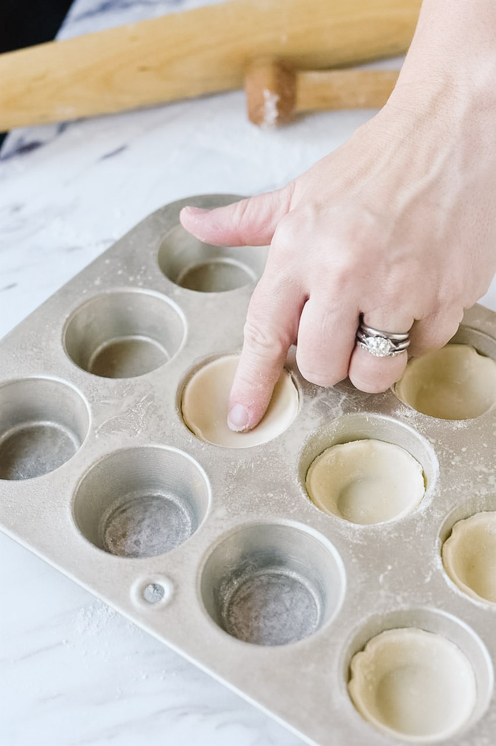 pushing pecan tassie dough into tin with finger