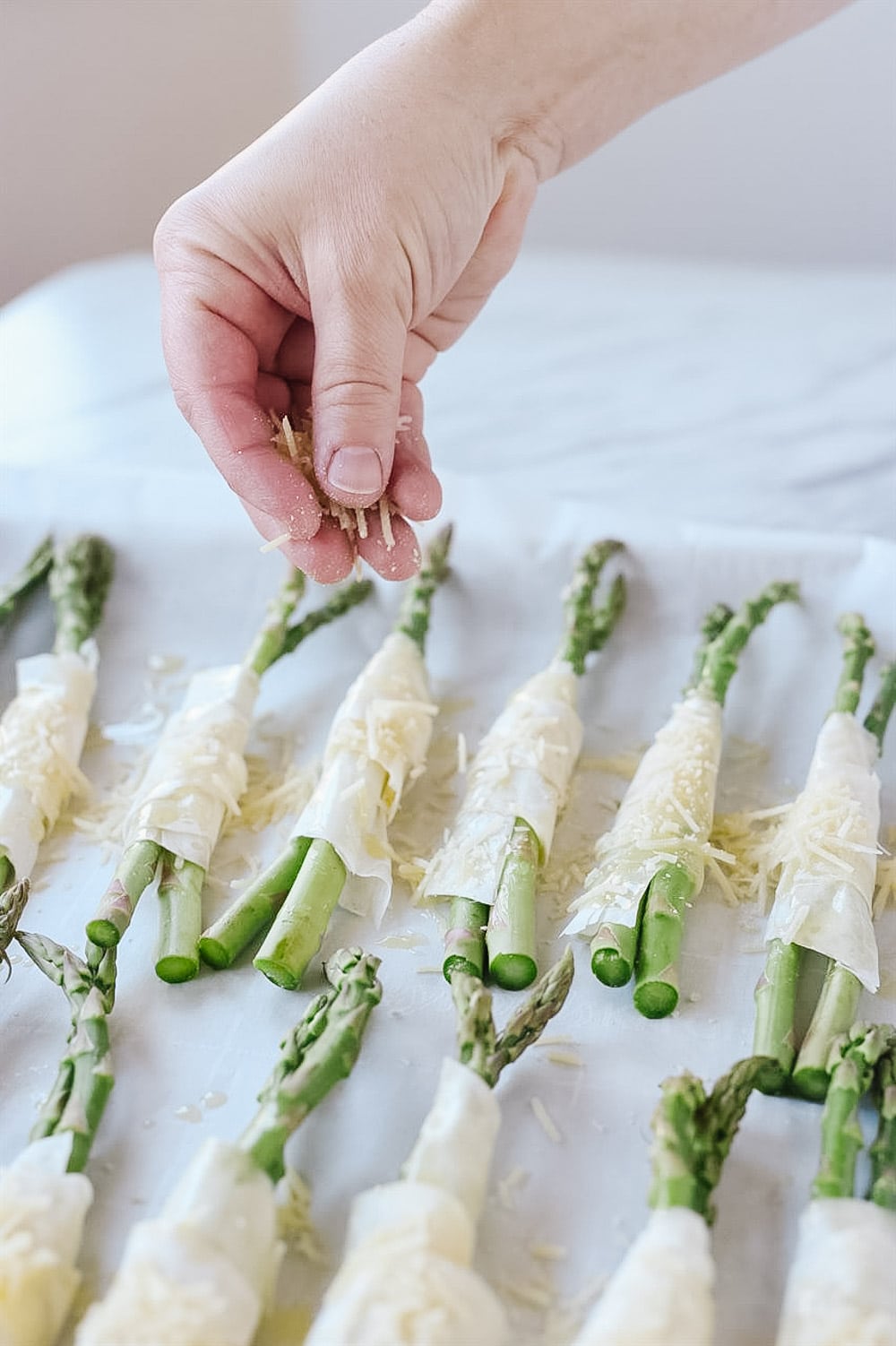 sprinkling phyllo wrapped asparagus with cheese.