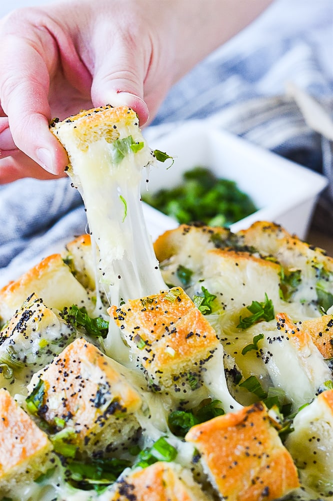 hand pulling cheesy bread