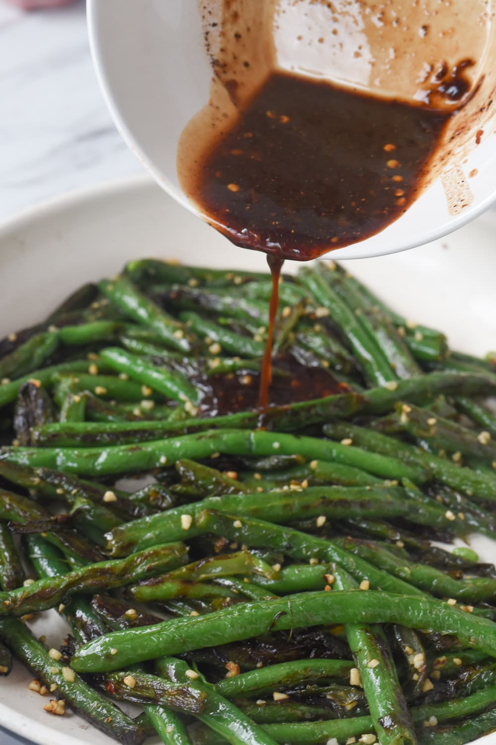 pouring sauce over chinese style green beans