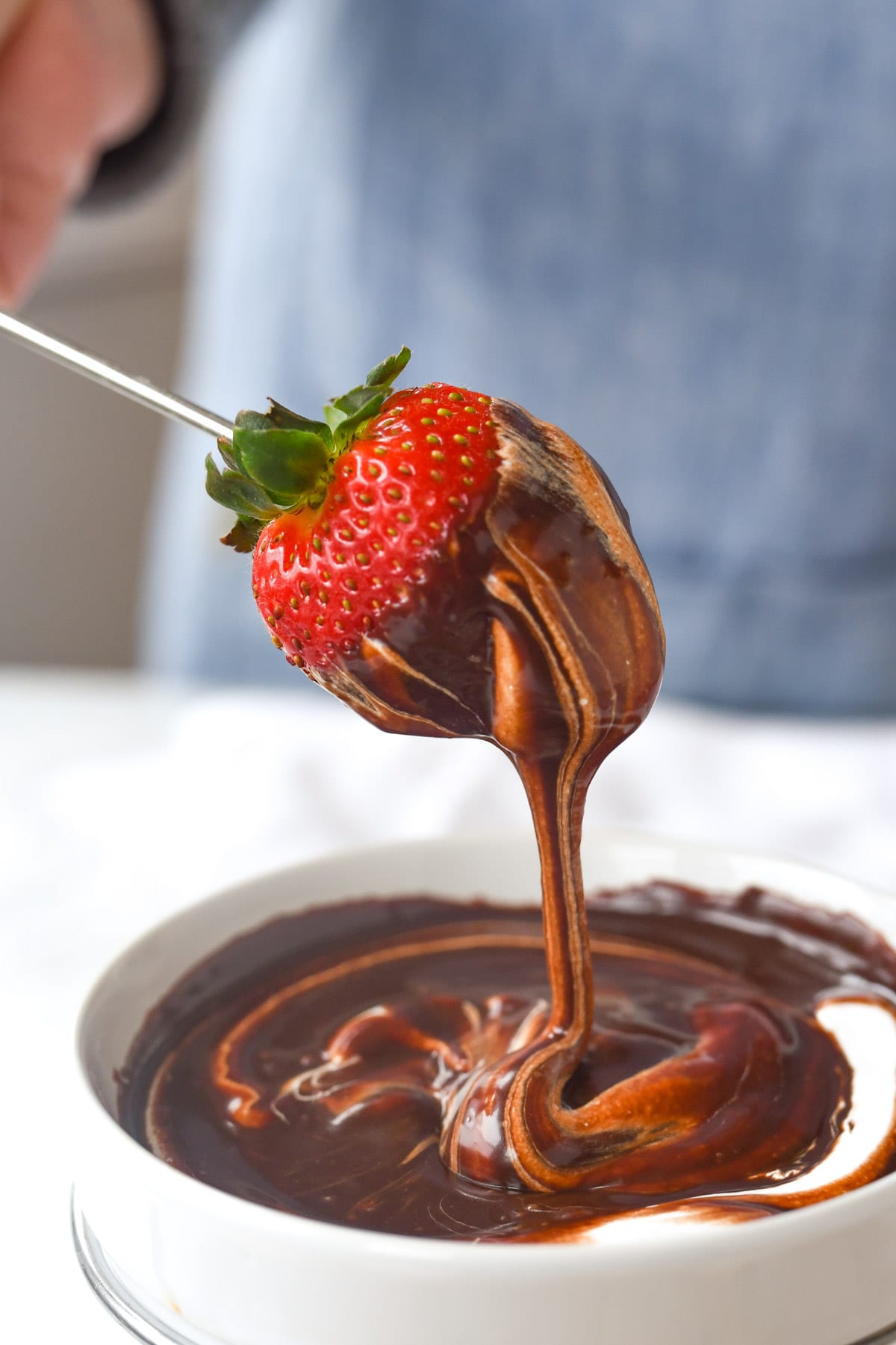 Strawberry dipping into chocolate fondue