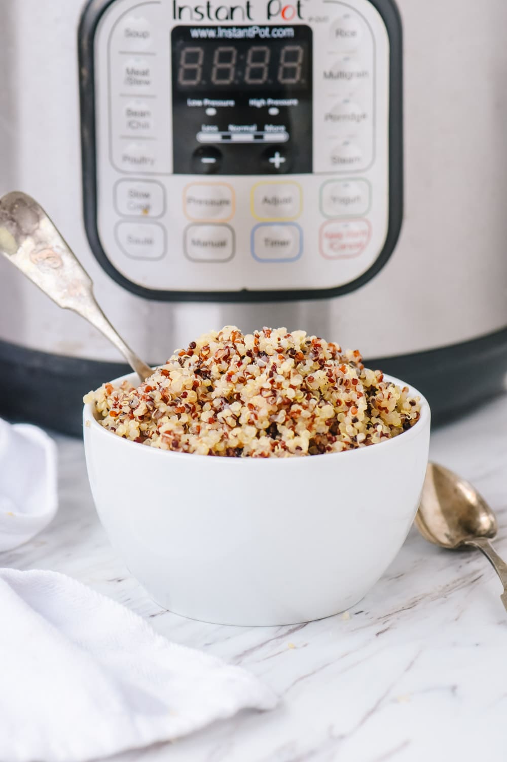 Instant Pot Quinoa bowl of quinoa in front of instant pot.