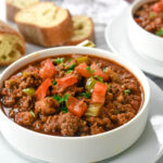 bowl of chili with tomatoes on top