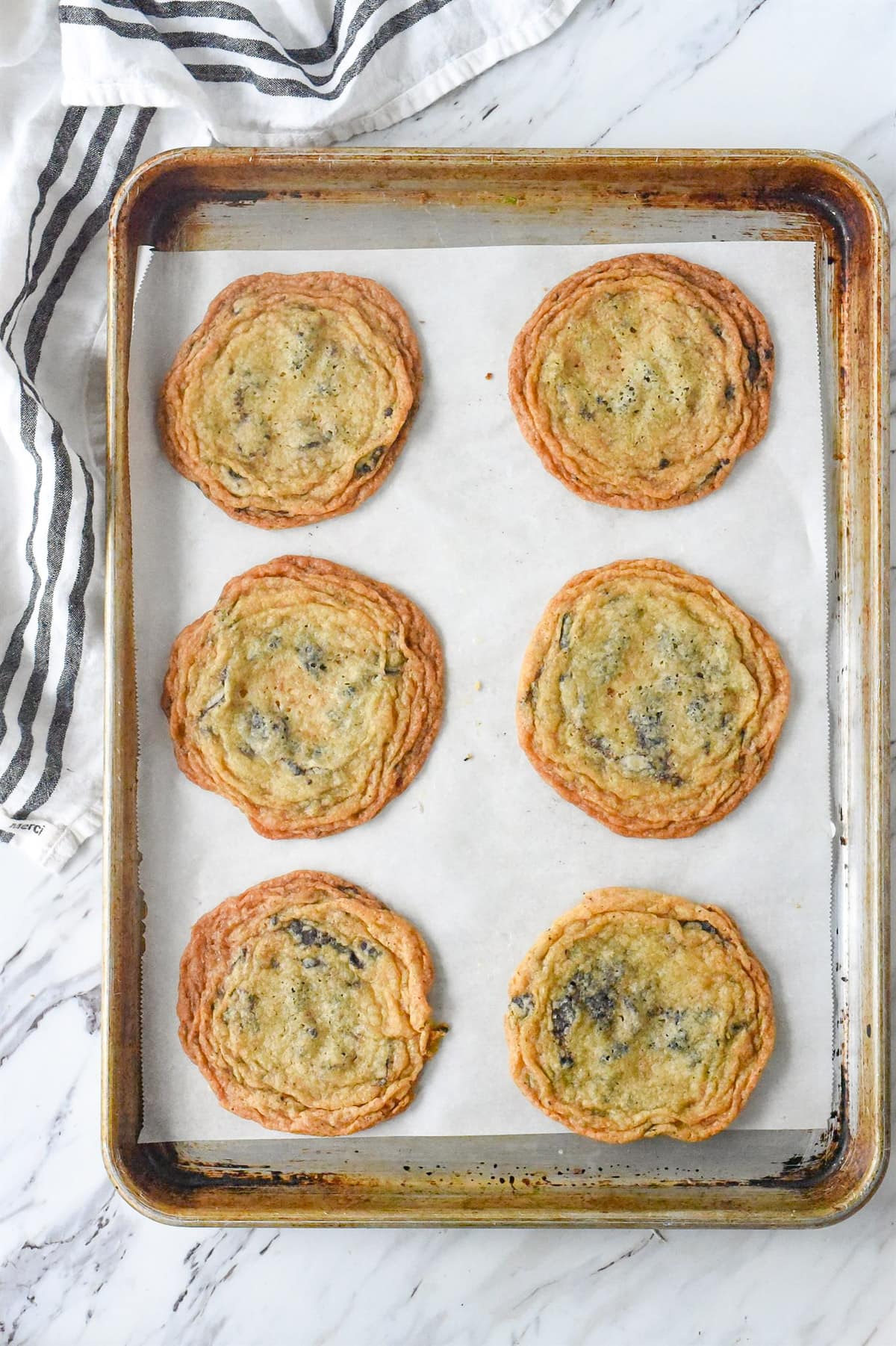 six crinkled chocolate cookies on a baking sheet