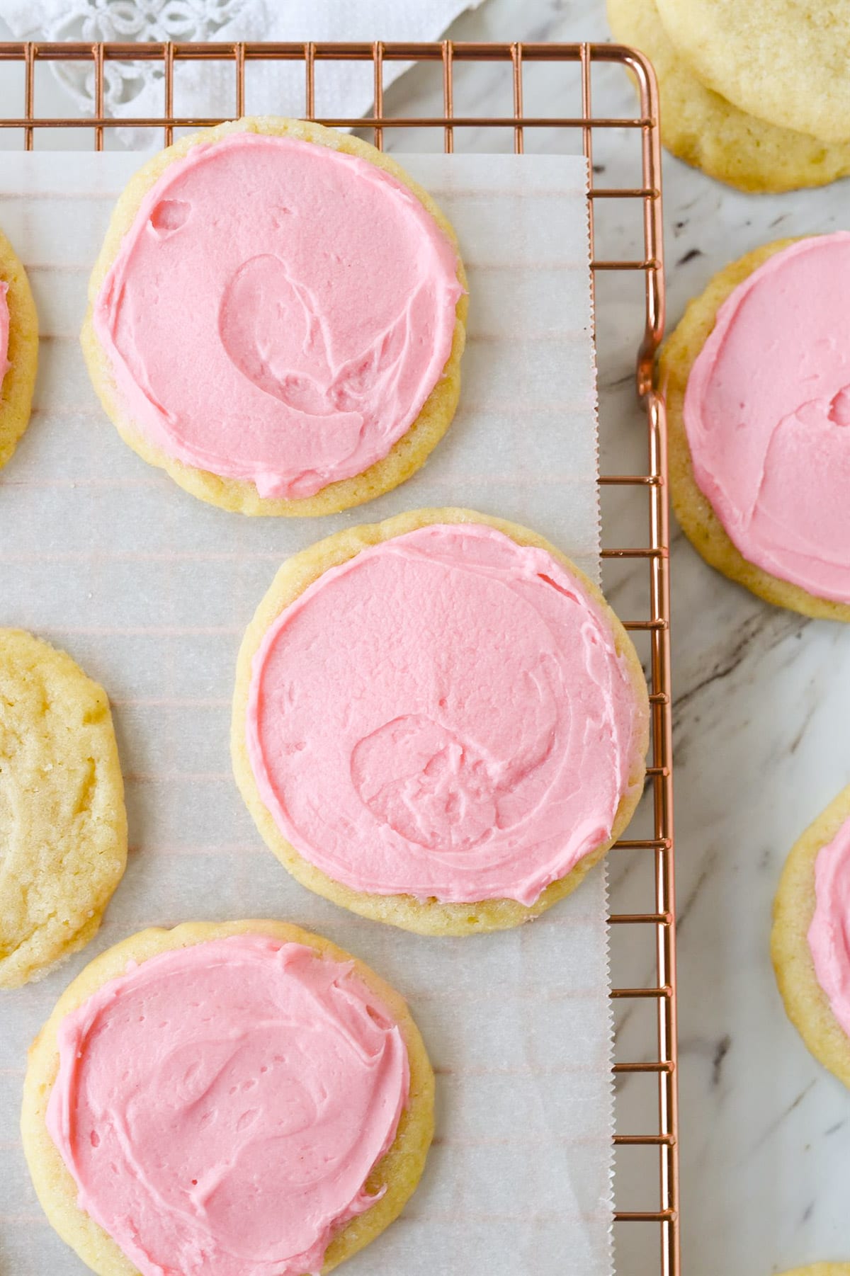 pink frosted sugar cookies on a cooling rack