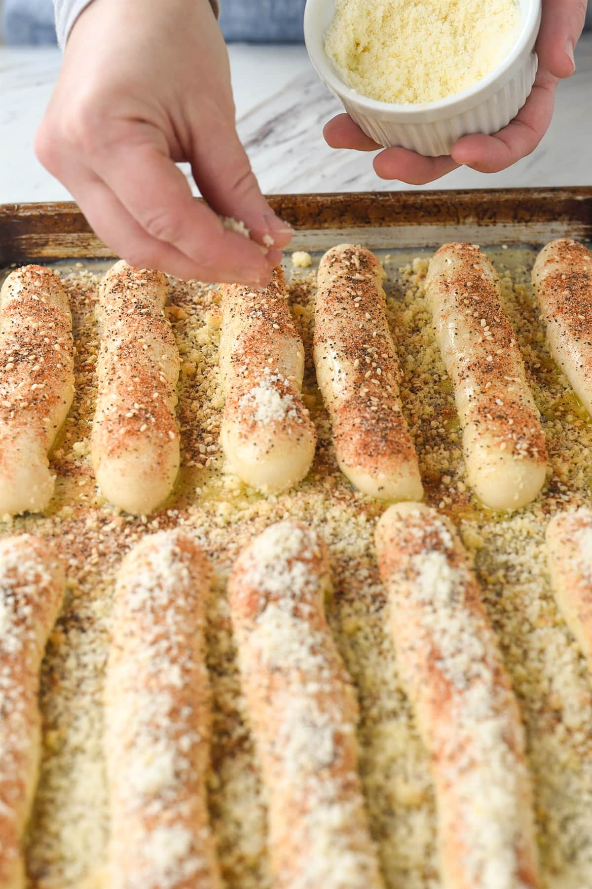 sprinkling cheese on breadsticks