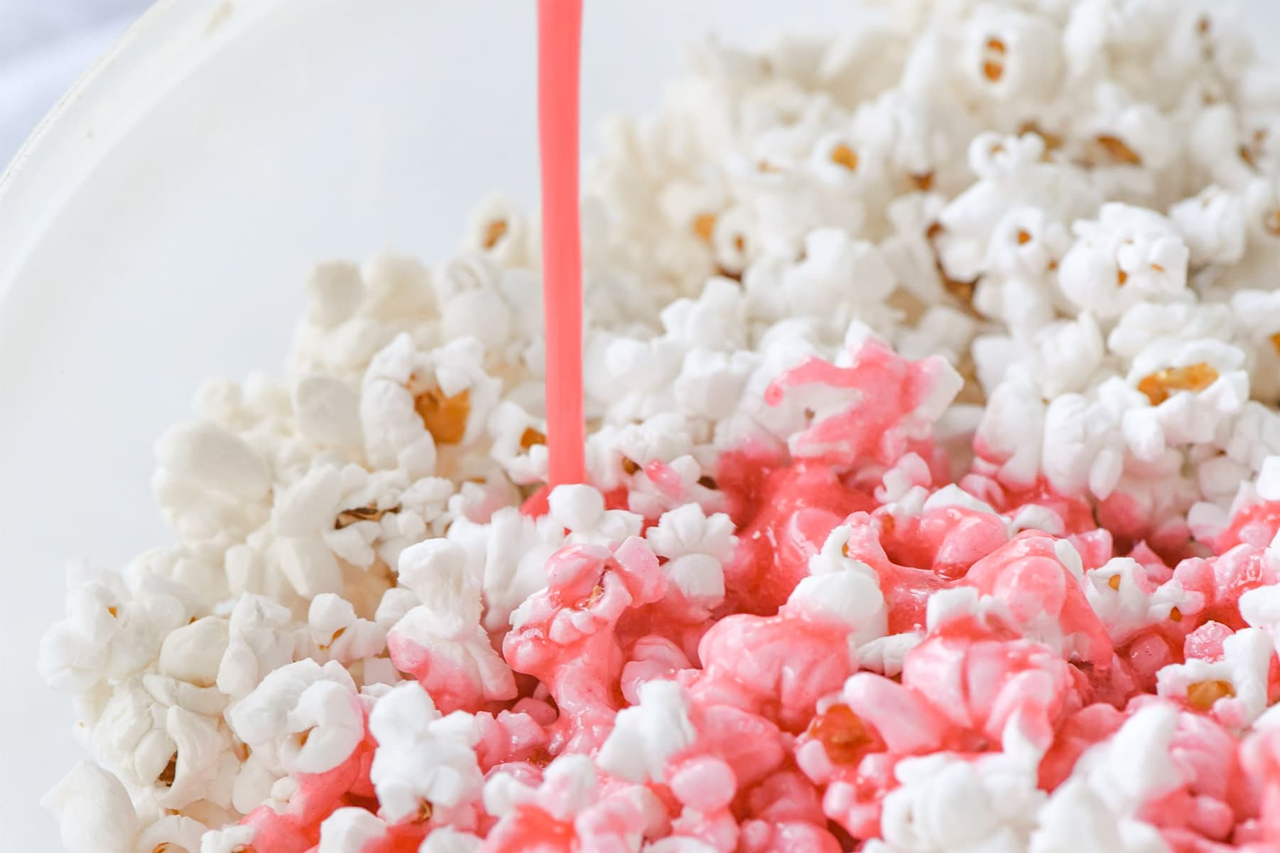 pouring syrup over pink popcorn