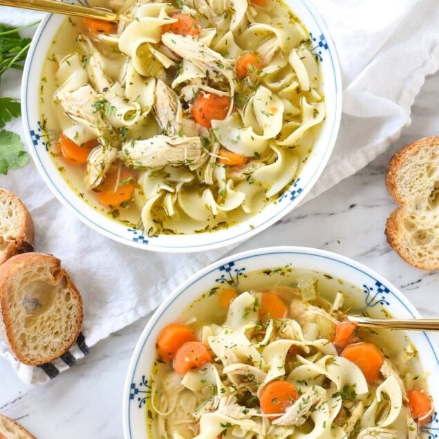 overhead shot of two bowls of chicken noodle soup