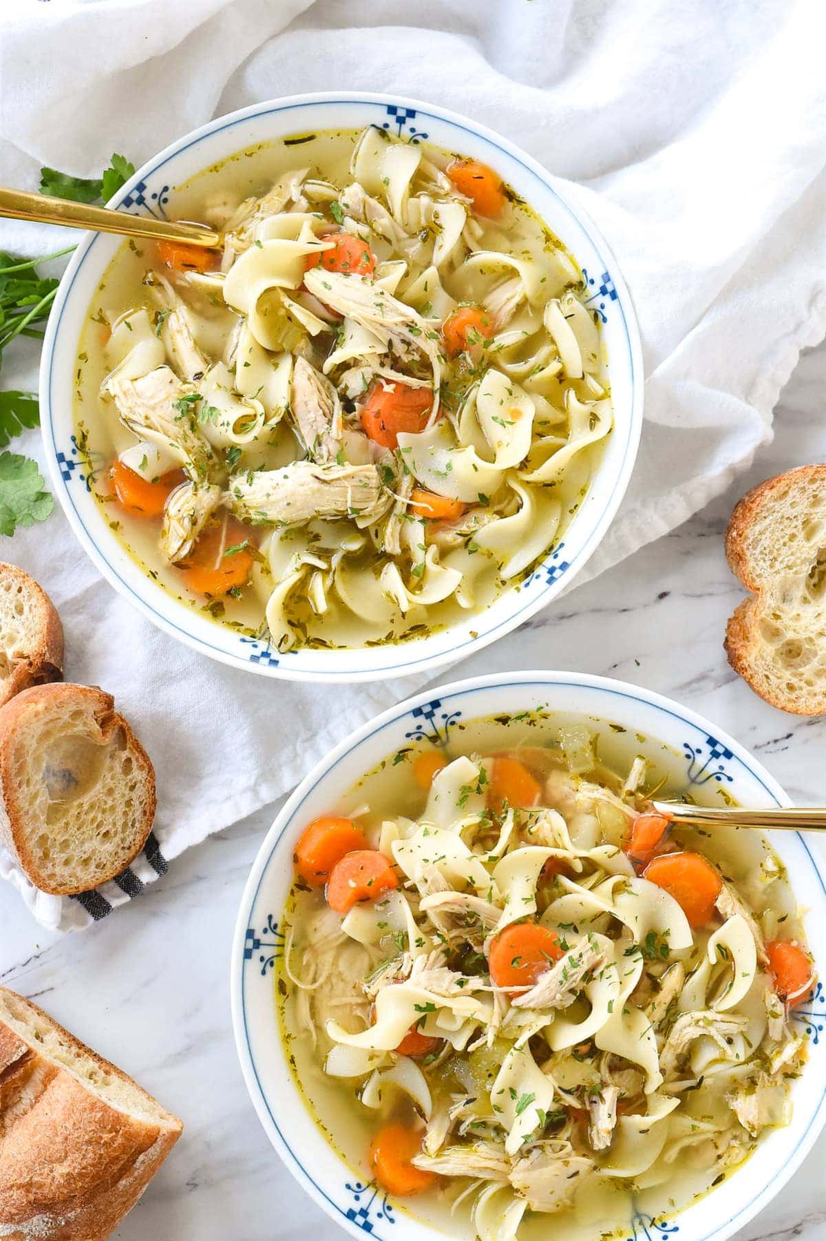 overhead shot of two bowls of chicken noodle soup