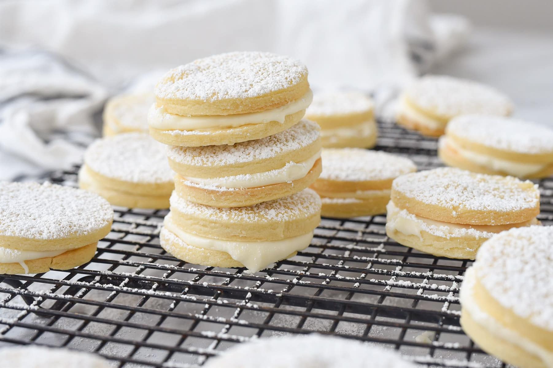 pile of lemon sandwich cookies on a cooling rack