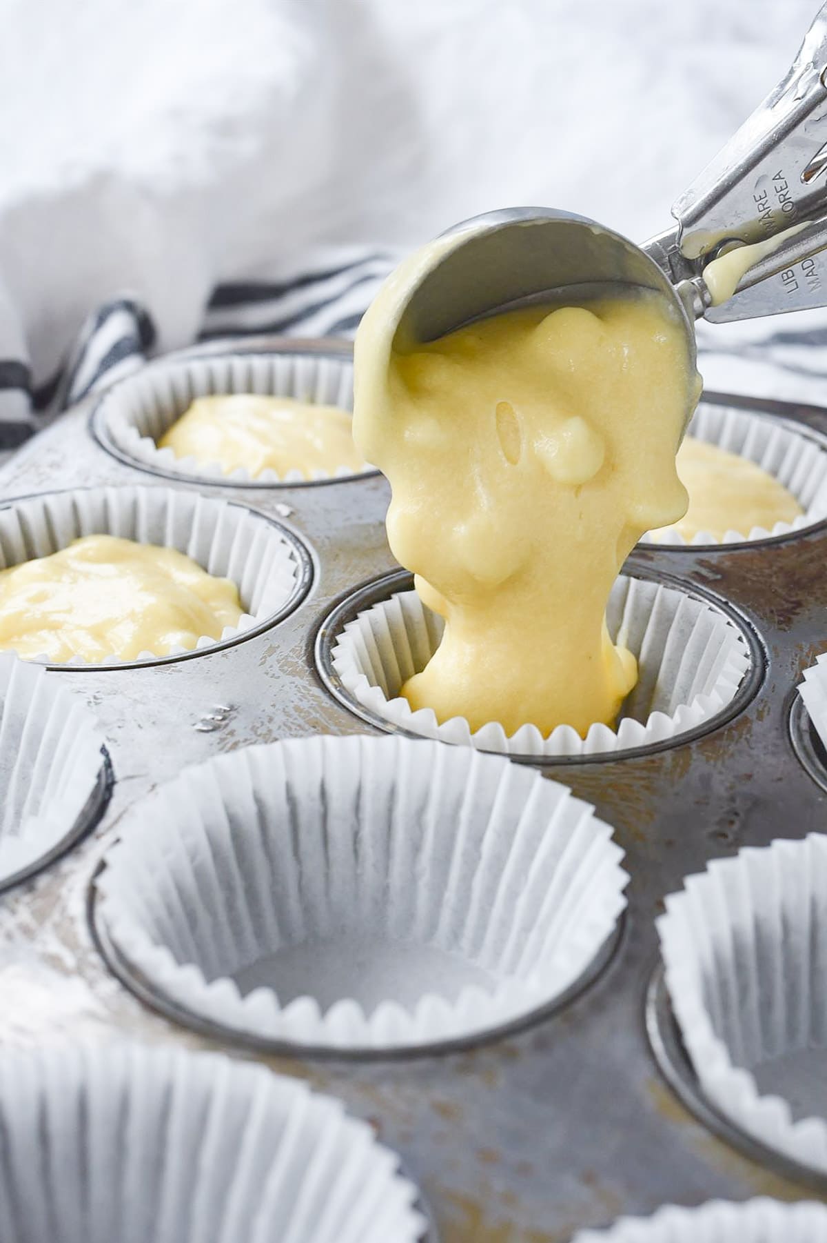 pouring muffin batter into muffin tin