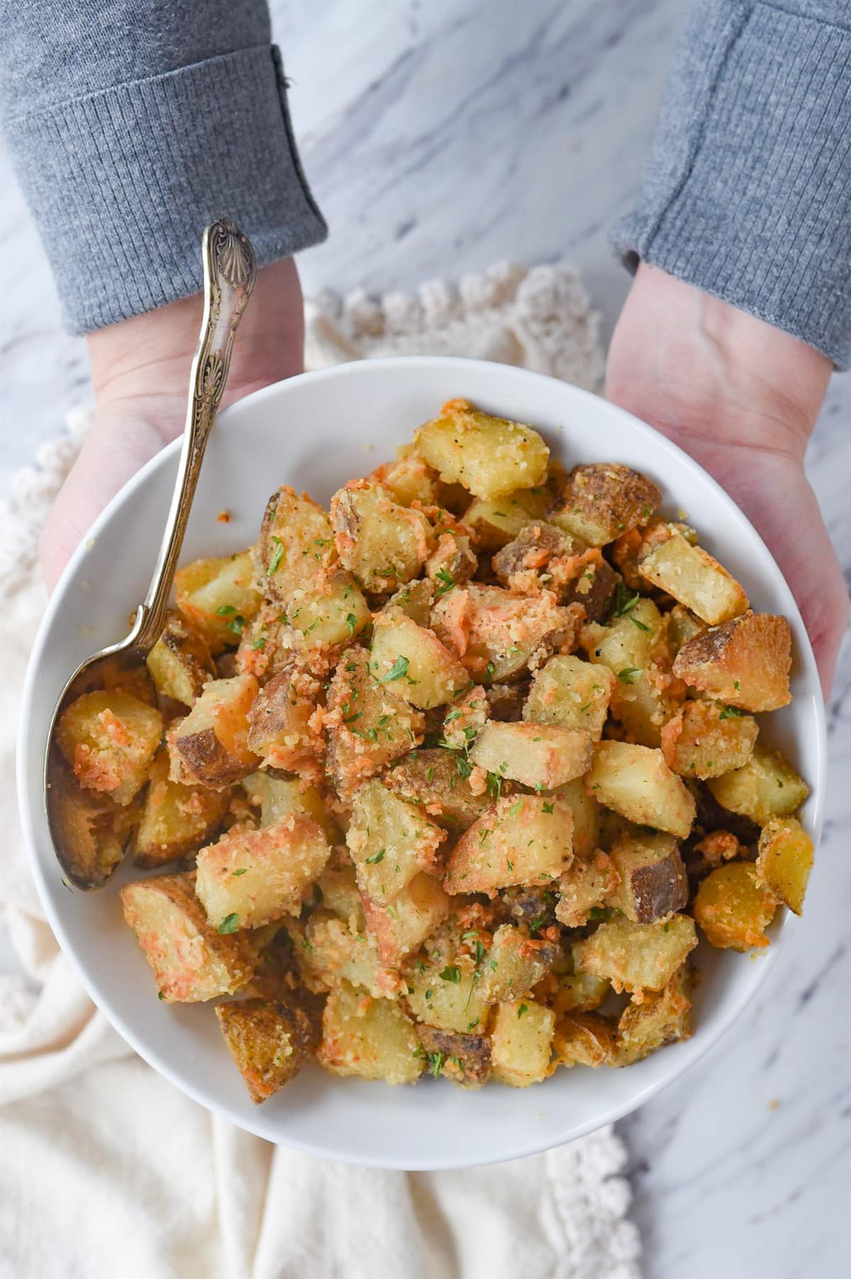 hands holding bowl of parmesan roasted potatoes