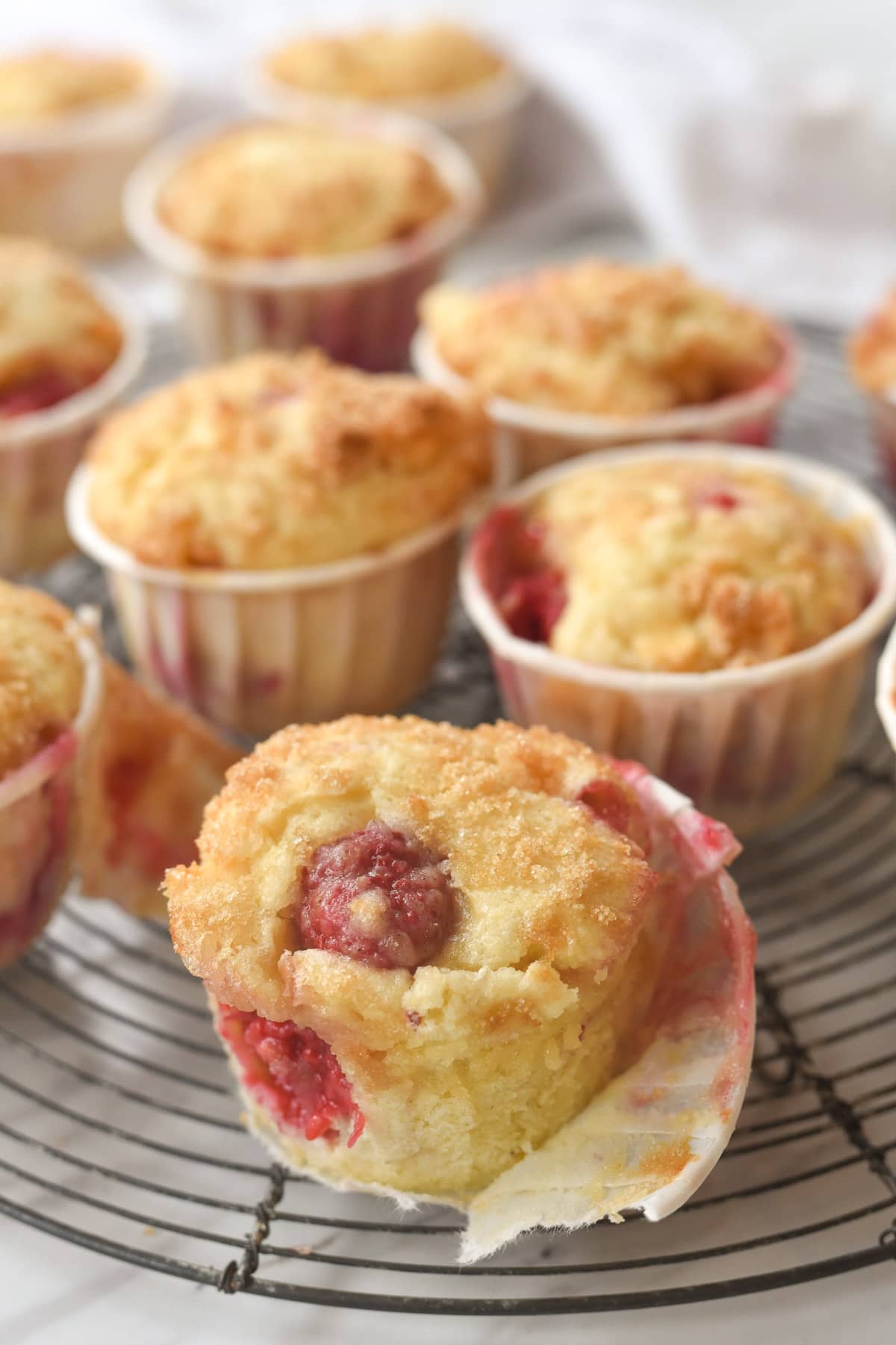 raspberry muffin unwrapped on a cooling rack