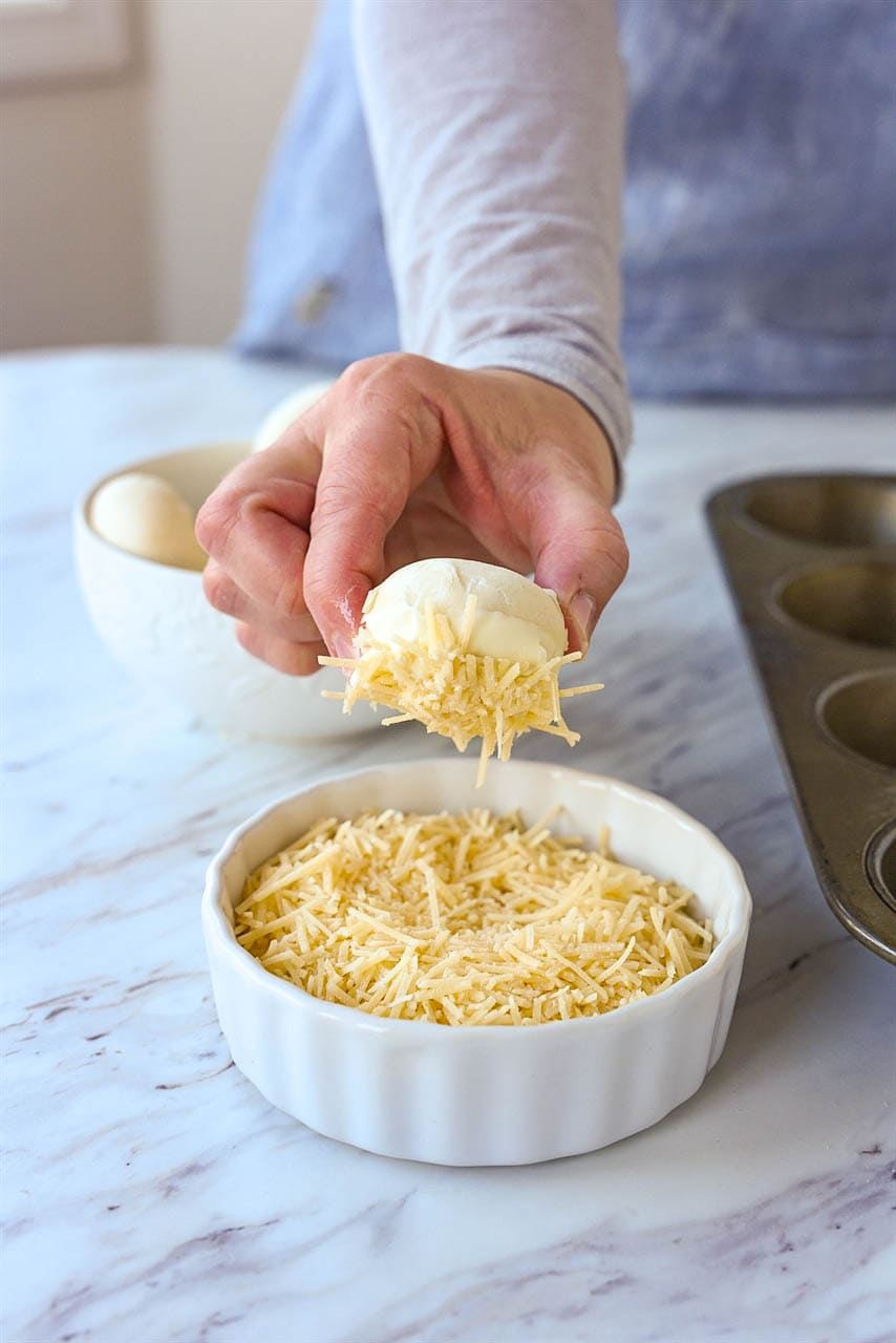 dipping frozen roll into parmesan cheese