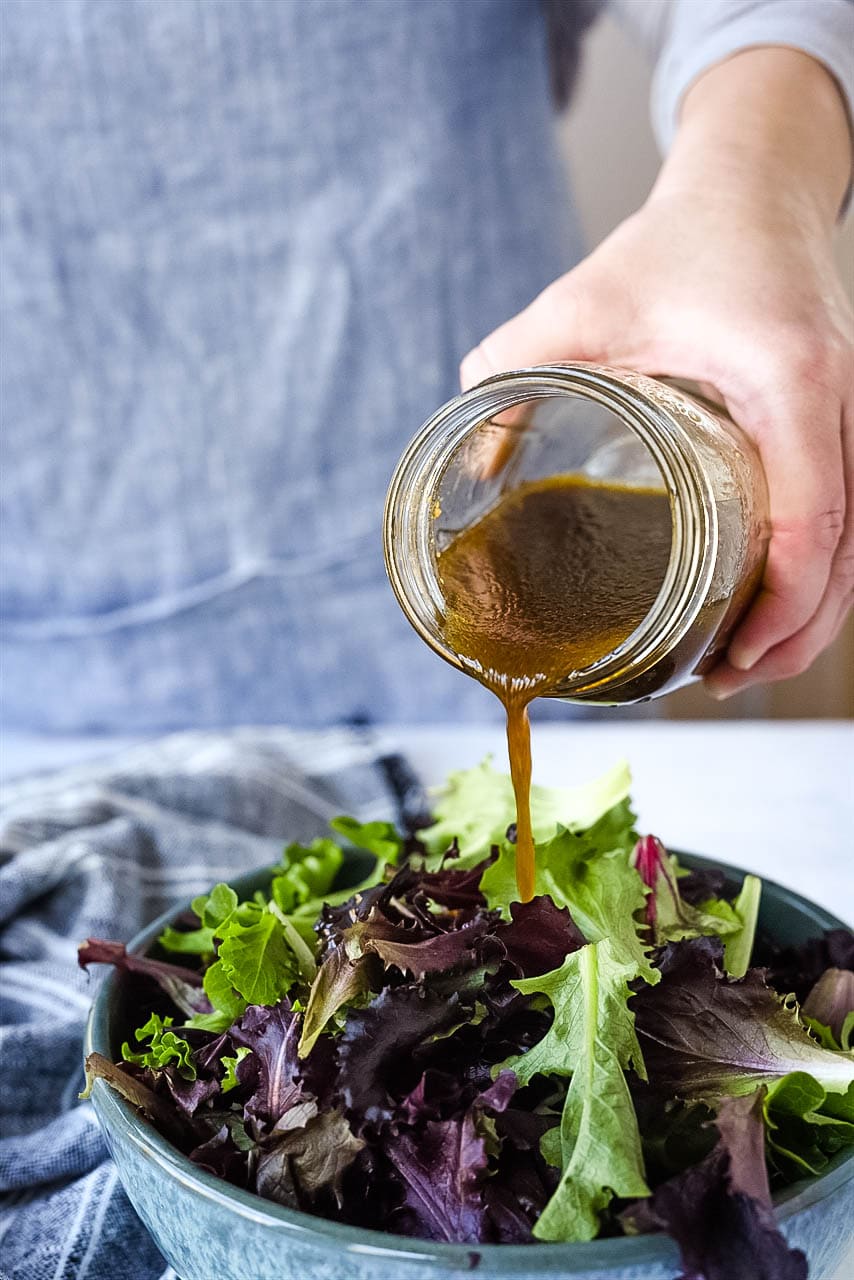 pouring vinaigrette over salad