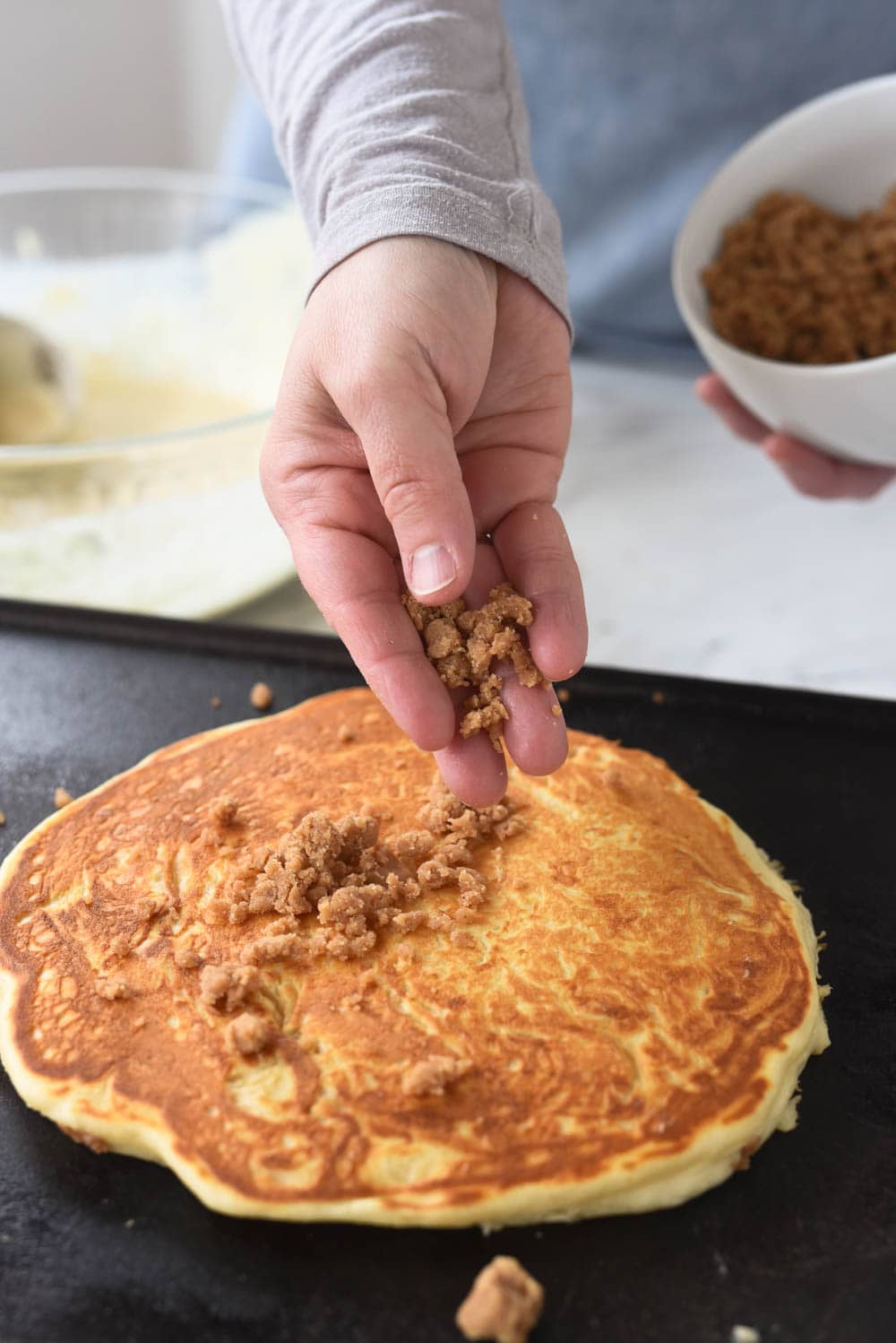 streusel topping being sprinkled onto pancake