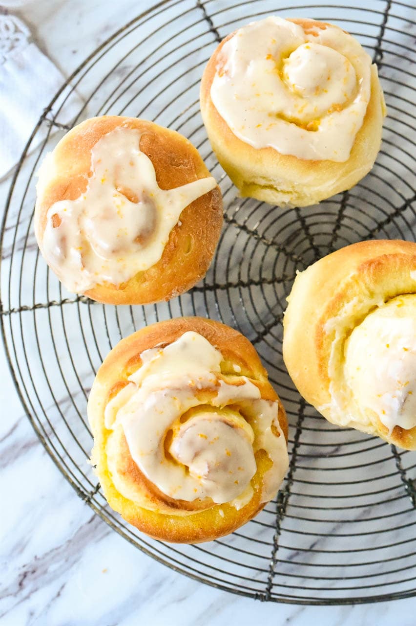 four orange rolls on a cooling rack