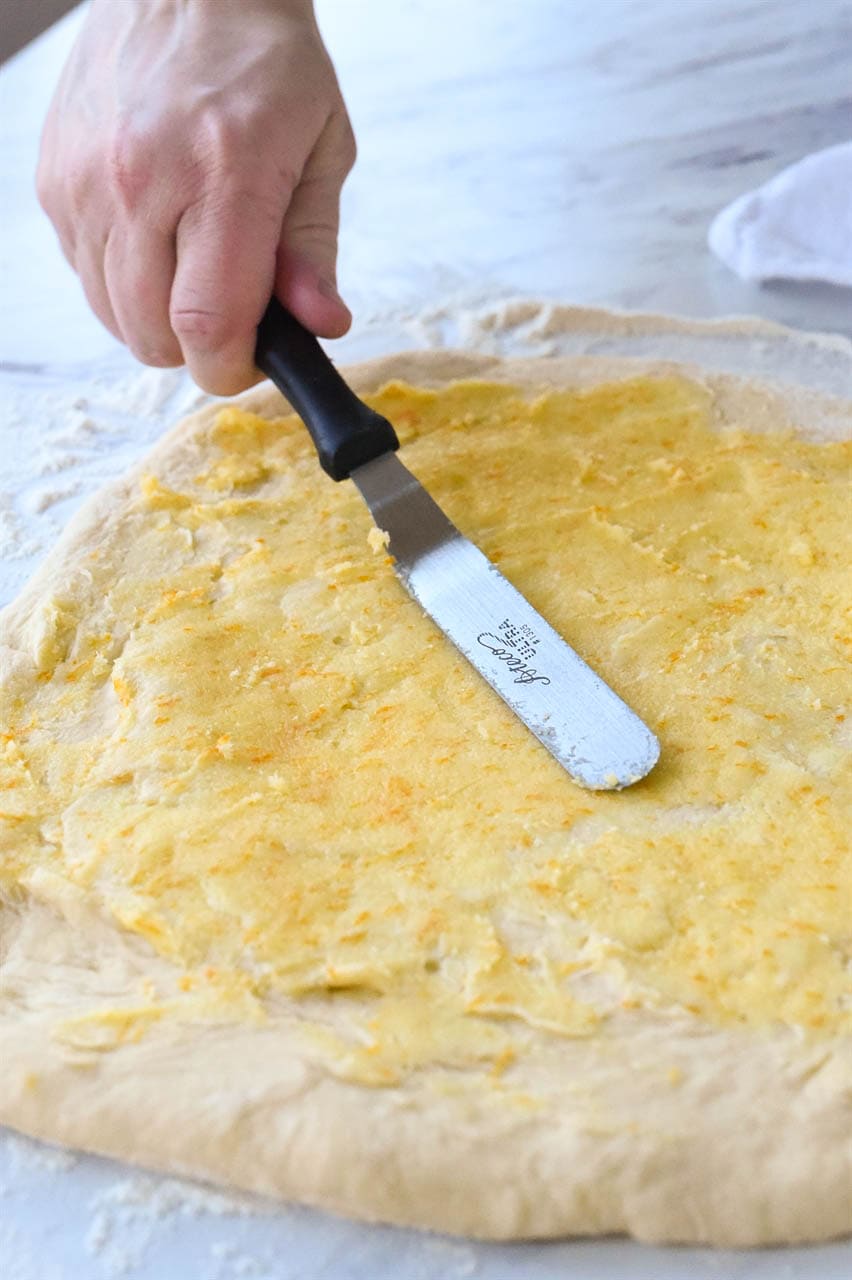 spreading orange roll filling on dough