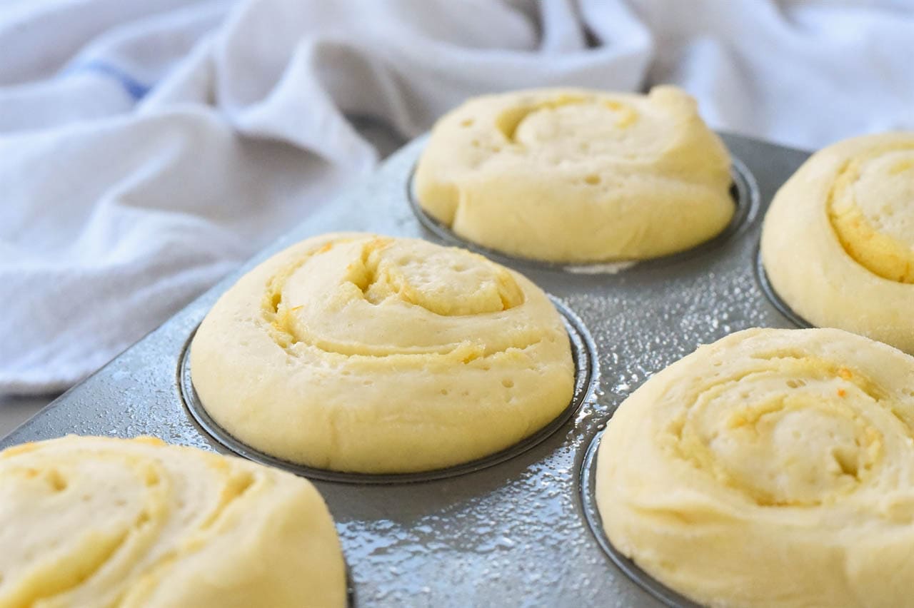 orange muffins rising in a muffin tin