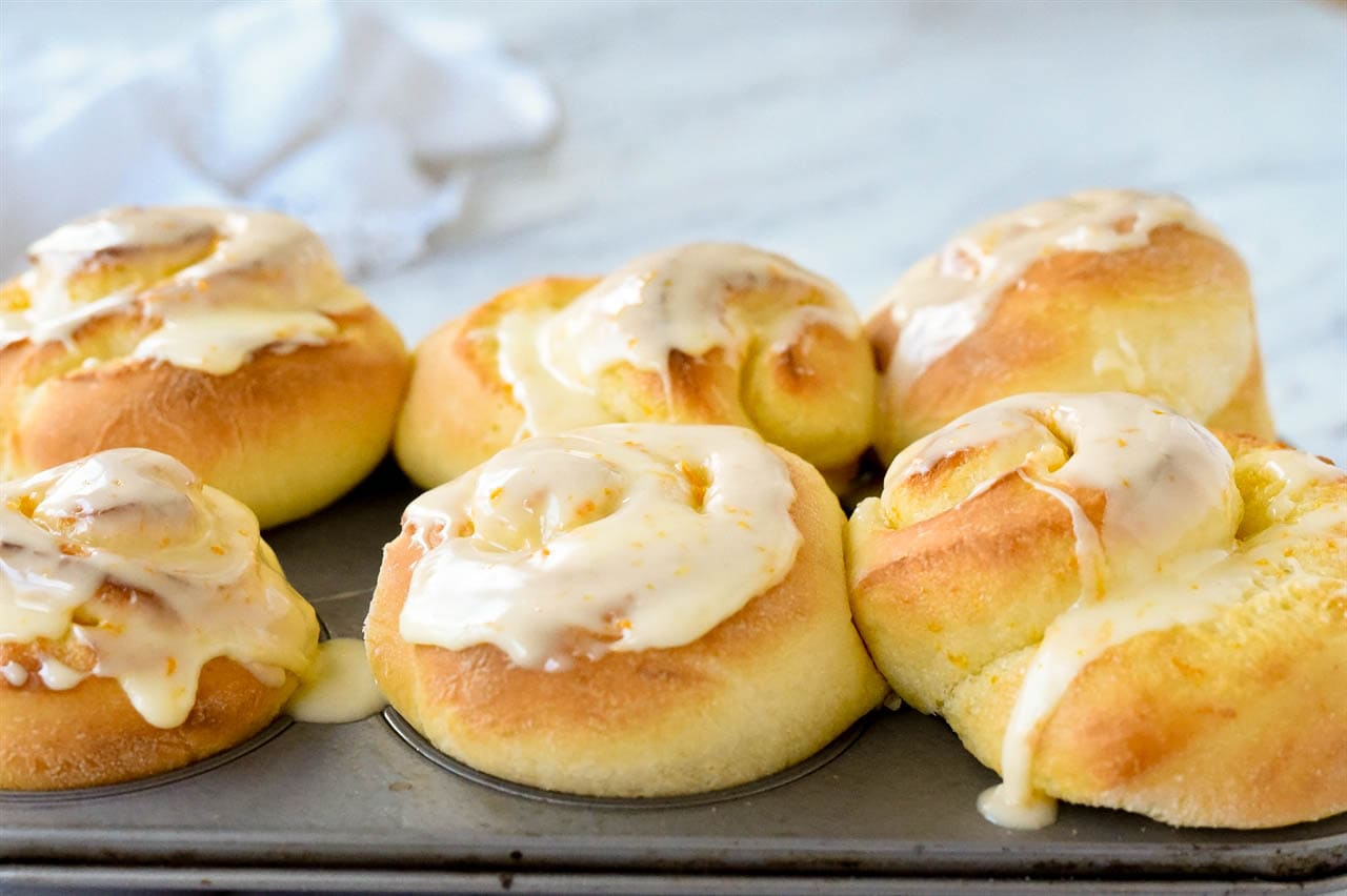 glazed orange rolls in a muffin tin