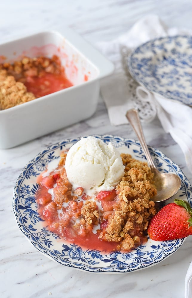 strawberry rhubarb crisp on a plate with a scoop of ice cream